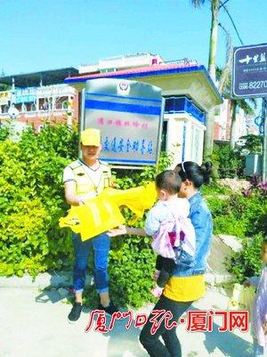 ▲劝导员正在向村民发放交通宣传环保袋。