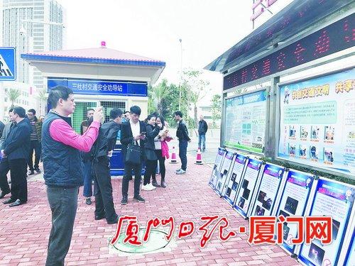 集美灌口镇三社村劝导站前,观摩人员仔细参观宣传栏布置,并拍下照片。