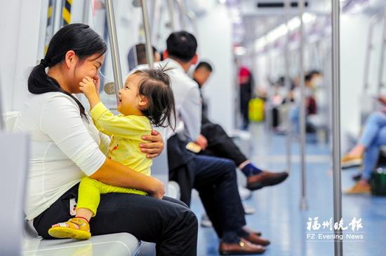 昨日,一位女士抱着孩子开心地乘坐地铁。